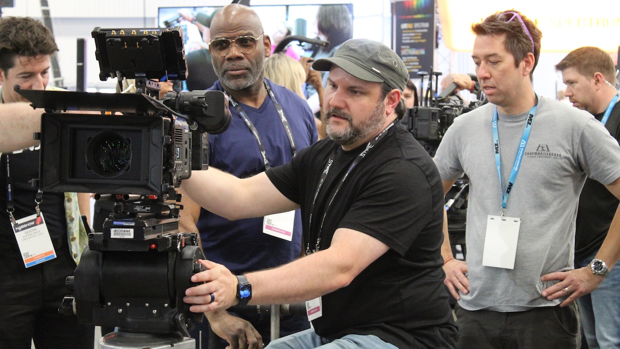 stoisko z wielkimi plakatami nadchodzących premier kinowych i tłumnie zwiedzający