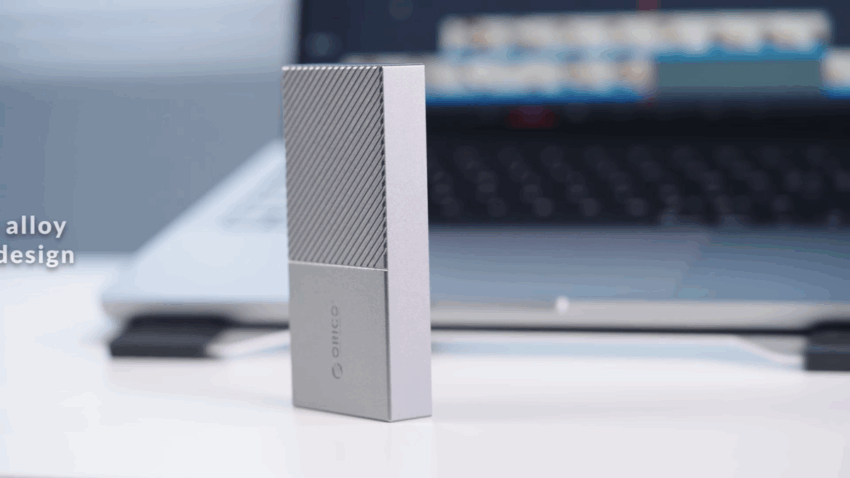 mężczyzna edytujący wideo na laptopie obok podłączonego dysku SSD